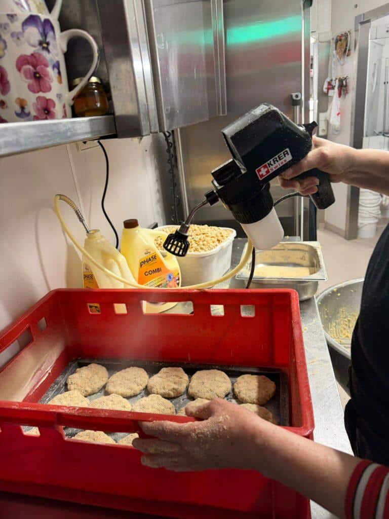 The KREATIVITY foodSPRAYER Pro in action at a butchery in Austria applying butterfat onto breaded schnitzel